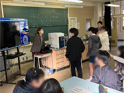 Children at Toyonaka Municipal Kitaoka Elementary School listen to an explanation of electron microscopes in a Hitachi High-Tech Fielding outreach class